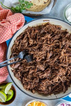 a bowl filled with shredded beef next to bowls of salsa