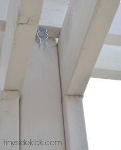 a blue pair of scissors hanging from the side of a white wooden structure with wood slats