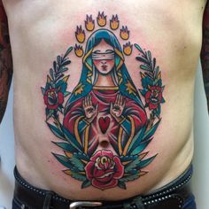 a woman with tattoos on her stomach holding a rose and praying to the virgin mary