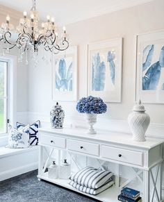 a white table with blue and white vases on it next to a chandelier