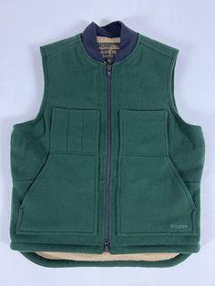 FEATURES Built with tightly-woven Mackinaw Wool Zipper-front closure Lined with high-pile Sherpa fleece Wool-blend rib-knit collar Dropped tail for added coverage Slotted and utility chest pockets; interior-chest pocket MANUFACTURING SKU: 20199228 Made in Bangladesh Material: 24-oz. 100% virgin wool + 11-oz. 74% polyester/14% acrylic/12% wool Sherpa fleece + 6-oz. dry finish Cover Cloth Brand new with tag. 1st quality! Made in Bangladesh. Measurements: Pit to pit: 24.5” Back center length (exclu Craftsman Clothing, Mens Down Vest, Drippy Fits, Work Vest, Cloth Brand, Wool Work, Plaid Vest, Down Vest, Wool Plaid