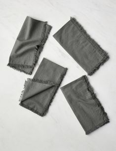 four pieces of gray linen with frays on them sitting on a white table top