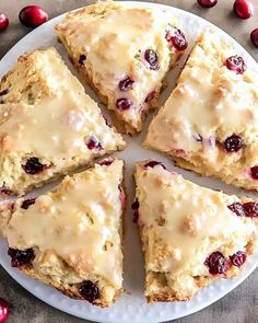 a white plate topped with scones covered in icing and cranberry toppings