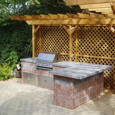 an outdoor bbq with grill and pergolated area