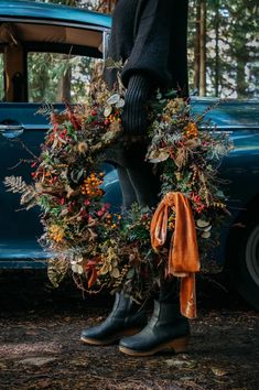 a person standing next to a car with a wreath on it