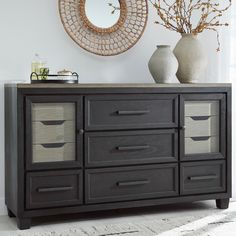 a black dresser with drawers and vases on top