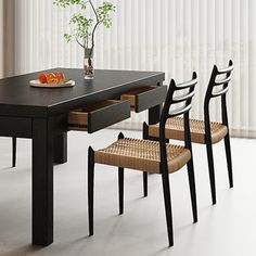 a dining table with four chairs and a bowl of fruit on it