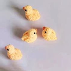 four small yellow crocheted animals sitting next to each other on a white surface