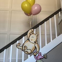 some balloons that are hanging from the ceiling and on top of a banister with a teddy bear