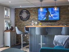 a living room filled with furniture and a flat screen tv mounted to the wall above a bar