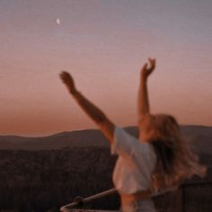 a woman standing on top of a roof with her arms in the air