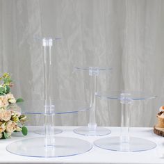 three clear vases sitting on top of a white table next to a flower arrangement