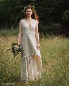 a woman in a white dress is walking through tall grass with flowers on her head