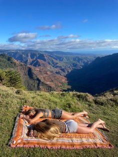 two women laying on a blanket in the mountains