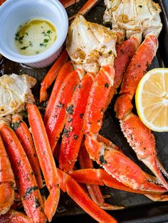 cooked lobsters and crab legs on a tray with lemon wedges, butter and parsley