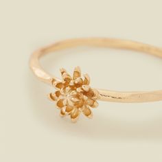 a gold ring with a flower on the middle and a small diamond in the middle