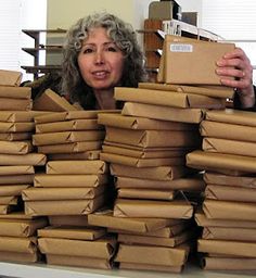 a woman standing behind stacks of cardboard boxes with her hands on top of the box