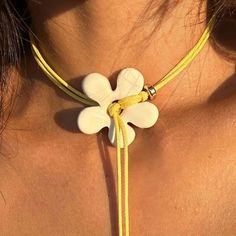 a woman wearing a yellow necklace with white flowers attached to it's neckline