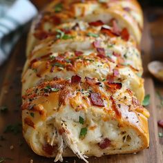 a cheesy bread with bacon and cheese on a cutting board