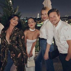 a group of people standing next to each other on top of a roof at night