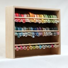 a wooden display case holding several different types of ribbons and ribbon holders on it's sides