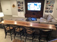 a living room filled with furniture and a flat screen tv mounted on a wall above a wooden bar