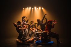 a group of people sitting on the ground with their arms in the air and one person standing