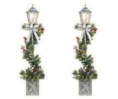 two christmas lights with bows and holly on them are hanging from the side of a wall