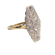 This exceptional Art Deco ring from circa 1920 features a rare 18 K yellow gold mounting with 1.5 mm shanking. It boasts a 24 x 15 fared shield adorned with 15 diamonds, 10 rose cuts 1.4 to 1.6 mm (1.5 to 2 points) and 5 old European cuts 3.1 mm (12 points). The diamonds have KT colors and VS clarities, with a total weight of 15 points. The gold weight is 2.1 dwt (3.26 grams). Formal Octagon Diamond Ring With Rose Cut Diamonds, Art Deco Diamond Ring In Yellow Gold With Accents, Art Deco Diamond Ring With Pave Setting, Heirloom Diamond Ring With Diamond Cut, Vintage Rings With Pave Setting, Gold Diamond Ring With Pave Setting In Vintage Style, 14k Gold Art Deco Cluster Ring, Art Deco Yellow Gold Diamond Ring With Accents, Formal Octagon Rose Cut Diamond Ring