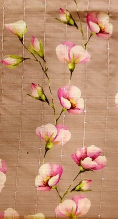 pink flowers and green leaves are hanging on a curtain with beaded netting behind them