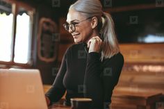 a woman sitting at a table with a laptop computer in front of her and smiling