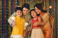 a family posing for a photo with sparklers in front of colorful lights on the wall