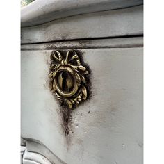 an ornate door handle on the side of a white painted wooden cabinet with gold accents