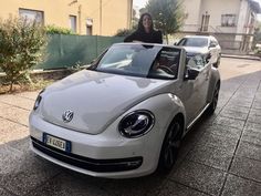 a woman standing next to a white car