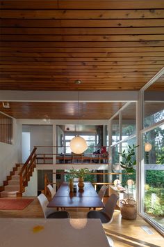 the dining room table is surrounded by white chairs and wooden beams, while the stairs lead up to the second floor