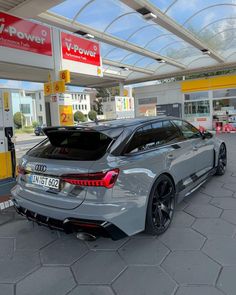 an audi car is parked in front of a gas station