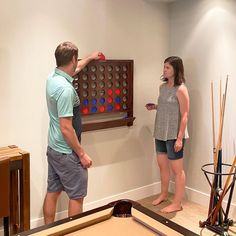 a man and woman standing in front of a pool table with balls on it,