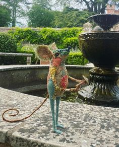 a statue of a rat standing in front of a fountain