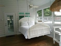 a white bed sitting in a bedroom next to a wooden floor and window sill