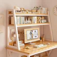 a desk with a computer on top of it next to a clock and other items