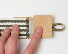 a hand is pulling up the edge of a piece of fabric with a pair of scissors