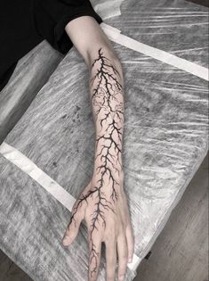 a person's arm and hand with lightning tattoo on the left side of their arm