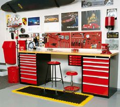 a garage with lots of tools on the wall and red cabinets in front of it