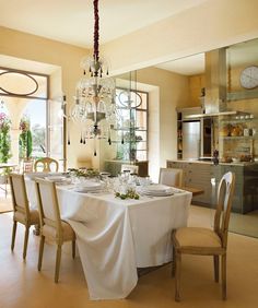 the dining room table is set with white linens and place settings for four people