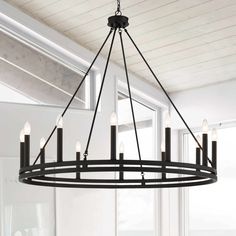 a black chandelier with candles hanging from it's centerpiece in front of a window