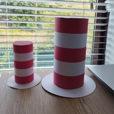 two red and white striped paper hats sitting on top of a wooden table next to a window