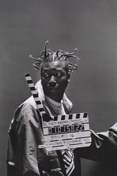 a black and white photo of a man holding a clap board with horns on his head