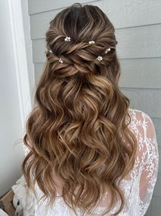 the back of a woman's head with long wavy hair and flowers in her hair