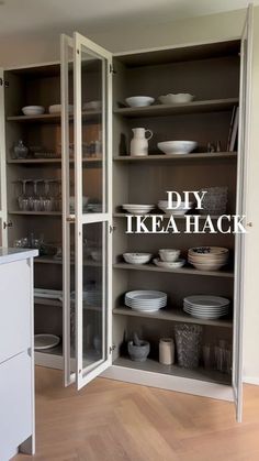 an open cabinet with plates and bowls on it in a room that has wood floors