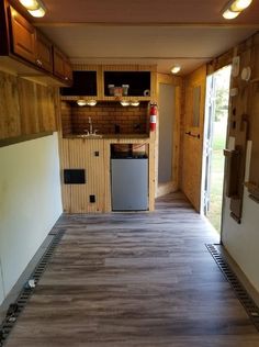 an empty kitchen with wood paneling and cabinets in the back ground, next to a large open door